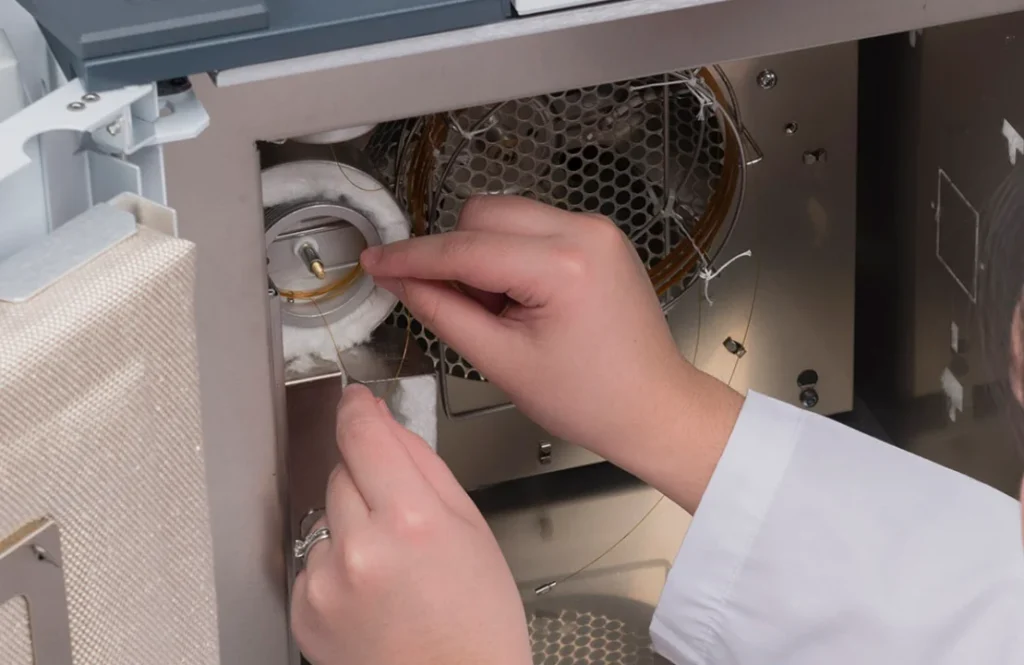 Laboratory technician replacing gc-ms column wire