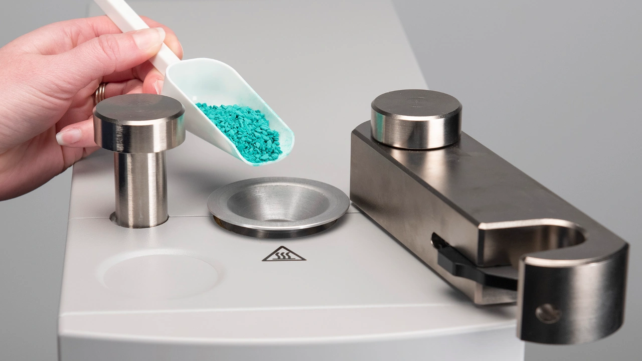 metallographer adding mounting media to mounting press