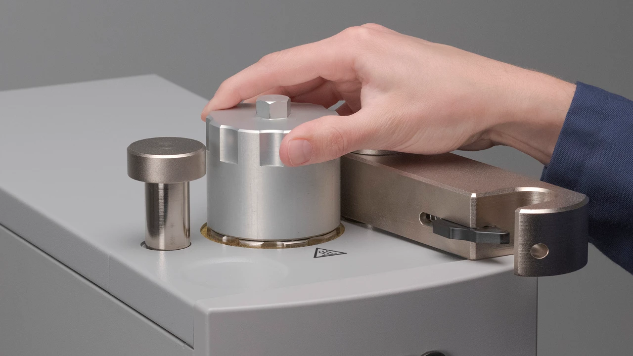 metallographer placing large sample sleeve into mounting machine