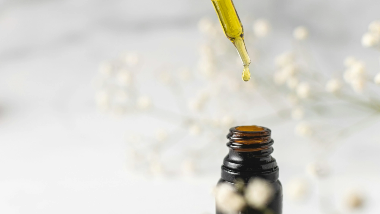 Essential oil dripping from pipette into bottle
