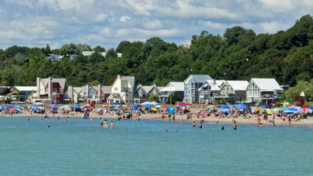 Beachgoers, sunbathers, and swimmers, near shorefront homes